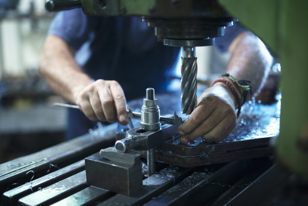 Worker operating industrial machine in metal workshop.